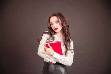 Modern business woman holds a notebook in hand. young student businesswoman in a white blouse on a black background.の写真素材