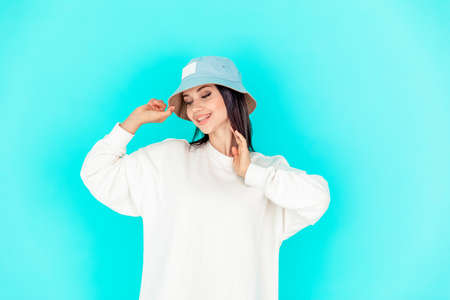 portrait of a beautiful girl in a denim cap and a white hoody on a blue background. concept of sport, summerの写真素材