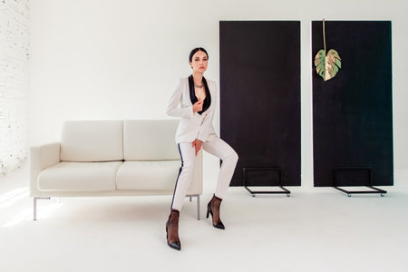 sexy businesswoman in a suit in a white photo studio. woman sitting on a white sofa.の写真素材
