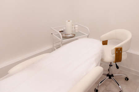 Cosmetologist's empty office with care cosmetics and massage table in a modern beauty salon. Medical cabinet interior.の写真素材