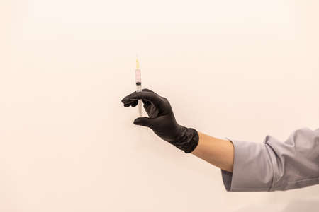 Doctor's hand in black glove with syringeの写真素材