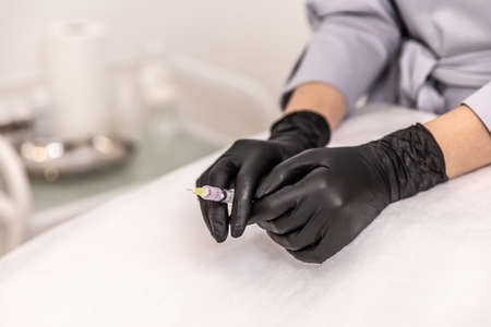 Doctor's hands in black glove with syringeの写真素材