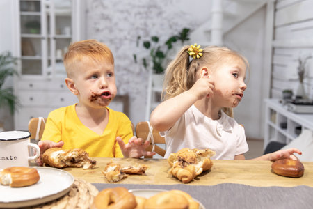 a little red boy and a little girl eat croissantsbrother and sister have breakfastの写真素材