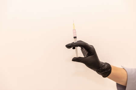 Doctor's hand in black glove with syringe