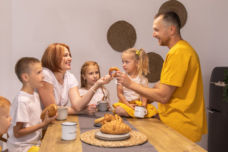 happy family having breakfast together at home. parents and children eat croisans. red peopleの写真素材