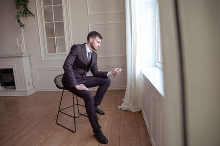 portrait of a brutal young man with a beard. a man looks at his watchの写真素材