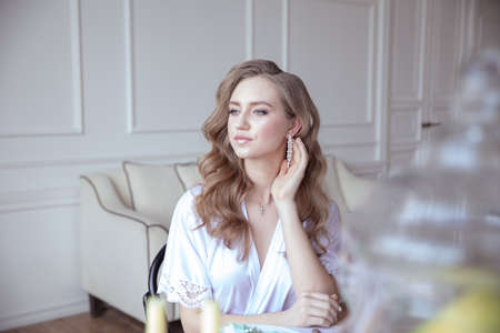 portrait of a beautiful young girl in a white robe in a bright interiorの写真素材