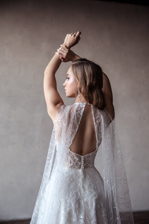 the bride in a beautiful wedding dress raises her hands. back viewの写真素材