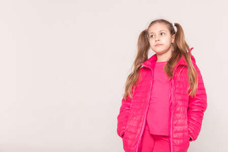 a girl with tails on a white background. baby in a pink jacket. copy spaceの写真素材