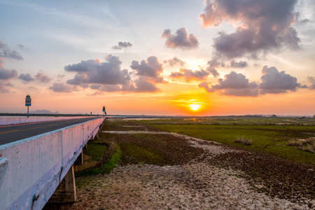 Bridge over the wet land under sunset. Many cloud on sky.の写真素材