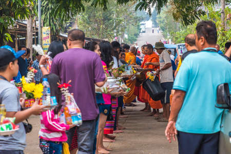 SAGKLABURI THAILAND- MARCH 11 : Unidentified tourists and unidentified people are give alms to a buddihist monk on March 11, 2016 at Mon Bridge.のeditorial素材