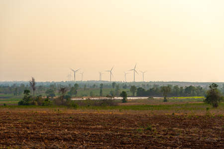 Warm tone in the sky and ground make you feel hot. The group of wind turbines is clean energy will make world to green again.の写真素材