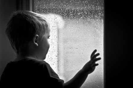 Boy looking at the rainの写真素材