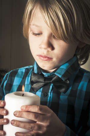 Boy looking at a christmas candleの写真素材