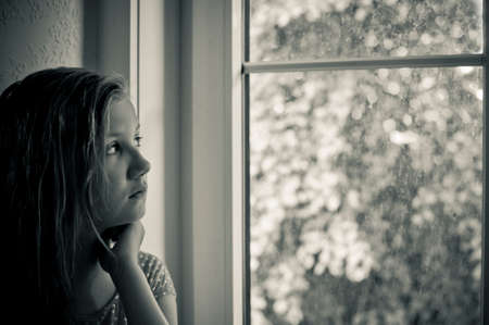 Worried girl at the windowの写真素材