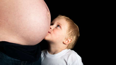 Child kissing pregnant womans bumpの写真素材