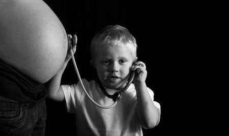 Child playing doctor with pregnant motherの写真素材