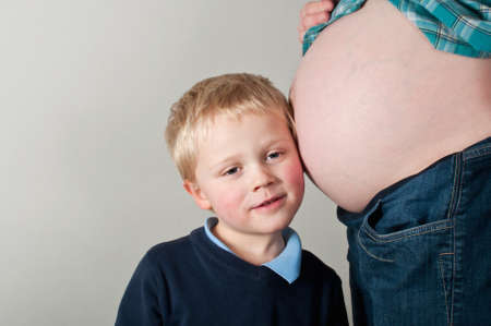 Child listening to pregnant mothers bumpの写真素材