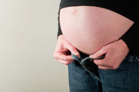 Pregnant woman struggling to fasten trousersの写真素材