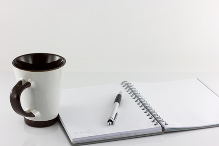 Cup of coffee and notebook isolate on white backgroundの写真素材