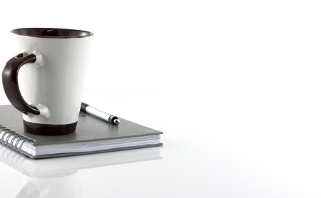 Cup of coffee and notebook isolate on white backgroundの写真素材