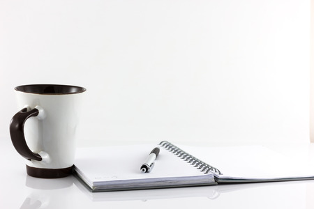 Cup of coffee and notebook isolate on white backgroundの写真素材