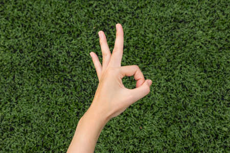 Girl Thumbs ok on background lawn.の写真素材