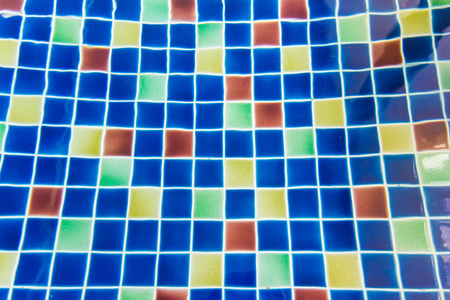 Sun reflection on the blue clear water ripples of swimming pool with mosaic bottomの写真素材