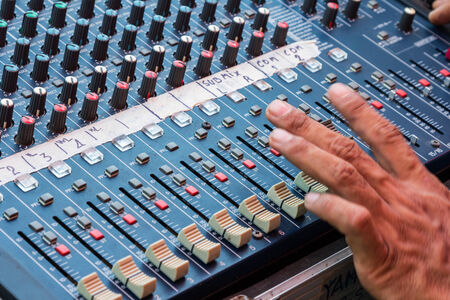 Audio mixing console closeup with handの写真素材