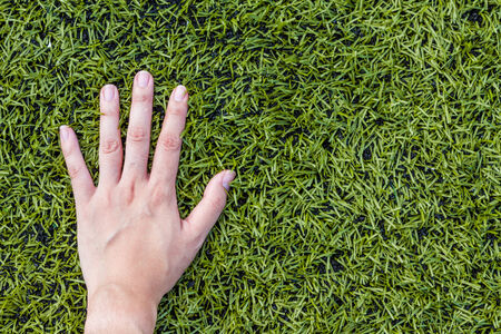 girl hand on soccer field grass backgroundの写真素材