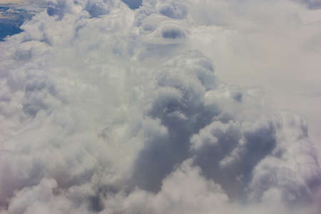 Fluffy white clouds and blue sky seen from airplane.