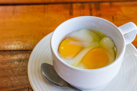 Soft boiled egg in white cup with spoon morning foodの写真素材