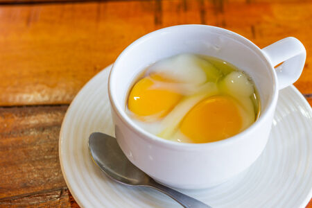 Soft boiled egg in white cup with spoon morning foodの写真素材