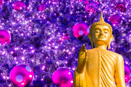 golden Buddha  on Christmas tree with colorful balls and gift backgroundの写真素材