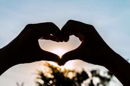 love shape hand silhouette at sunset backgroundの写真素材