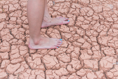 Nake wooman foot walk on walk on cracked earth backgroundの写真素材