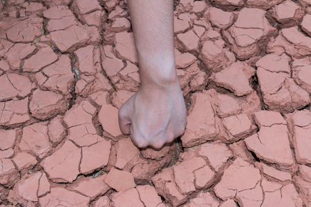 Fist hands on dry earth/Crack earth backgroundの写真素材