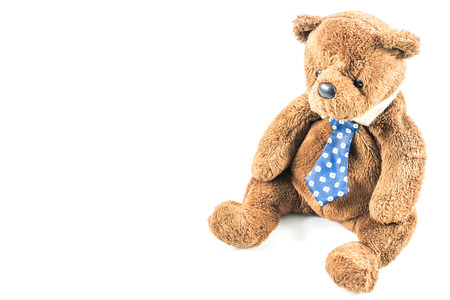 Old brown teddy bear with necktie on white backgroundの写真素材