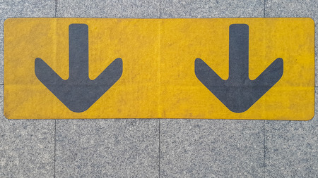 arrow sign in yellow color painted on black on the waiting zone for train, subwayの写真素材