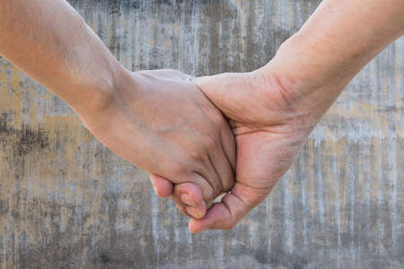 Lover hold hand on aged vintage gray cement wall texture backgroundの写真素材