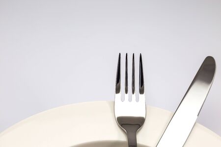 Stainless steel fork and knife on a white plate isolated on white backgroundの写真素材