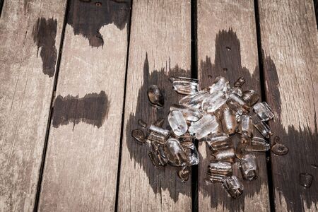 Ice melting on a brown wooden board backgroundの写真素材