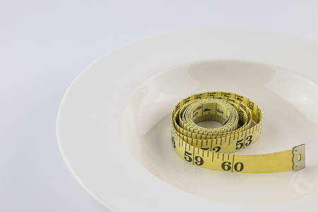 Tape measure with on white plate isolated withe background