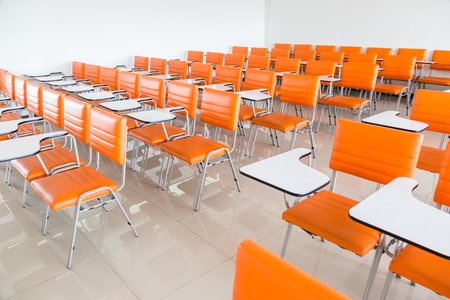 classroom with many orange armchairs backgroundの写真素材