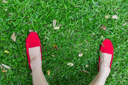 Red shoes girl on green grass backgroundの写真素材