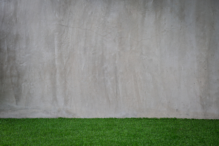 Green grass artificial turf pattern with gray cement wall backgroundの写真素材