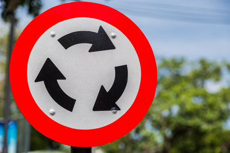 Roundabout Road Sign for Traffic with green bokeh backgroundの写真素材