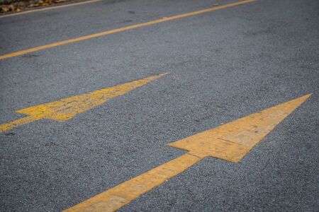 Two yellow arrows old and new  directionon asphalt road backgroundの写真素材