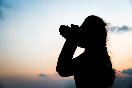 Silhouette  photographer taking a picture on sunset backgroundの写真素材