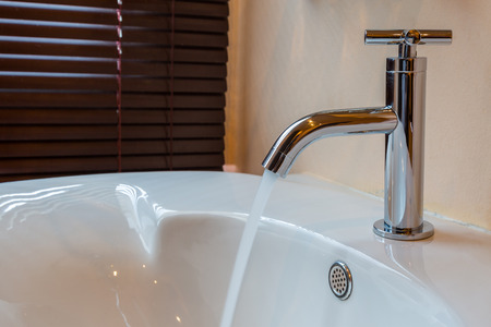 Modern chrome tap faucet with running water use for backgroundの写真素材